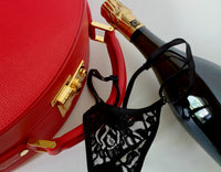 Valigia in pelle rossa, tanga di pizzo nero e bottiglia di champagne premium.