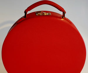 Valigia in pelle rossa a forma di cappelliera.