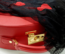 Load image into Gallery viewer, Babydoll nero appoggiato su una valigetta rossa.

